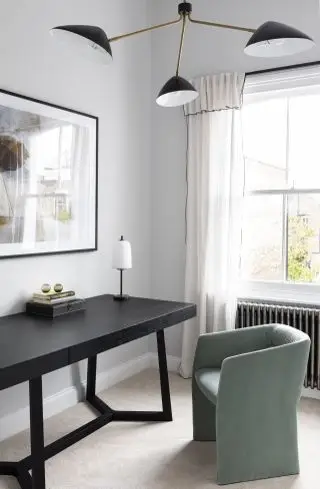 domácí kancelář s černým stolem, zelené křeslo, stolní lampa, retro závěsné světlo, radiátor, šedé stěny, umělecká díla, závěsy, koberec