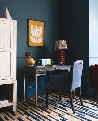 domácí kancelář s ombre stěnami, žlutá umělecká díla, stůl, modrá čalouněná židle, modrý a krémový koberec, červená lampa, úložná jednotka