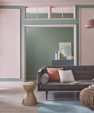 Sofá marrón en una sala de estar rosa y verde