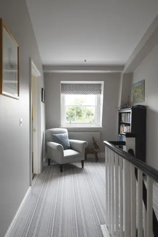 Hjemmebibliotek med blå hyller og stige, sofa og lenestol
