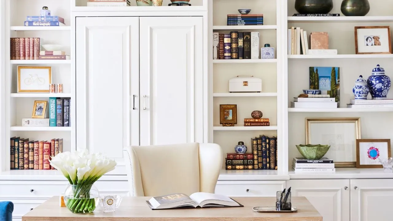 Et helt hjemmekontor med indbyggede hylder og et skrivebord i træ, bøger og nipsgenstande, der pryder hylderne' loading='lazy' title=