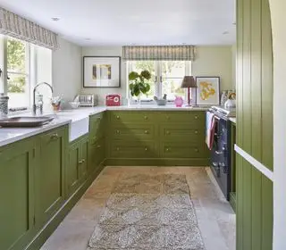 Uma cozinha verde com persianas listradas projetada por Vanrenen GW Designs