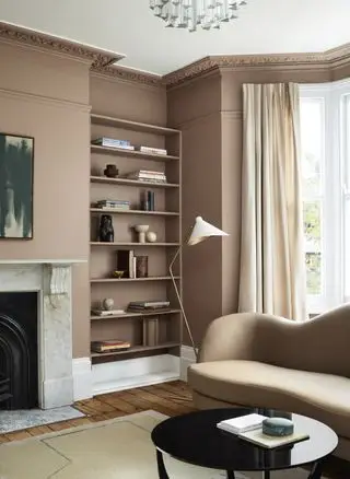 stue med sopp/brune vegger, bokhylle, tregulv, buet sofa