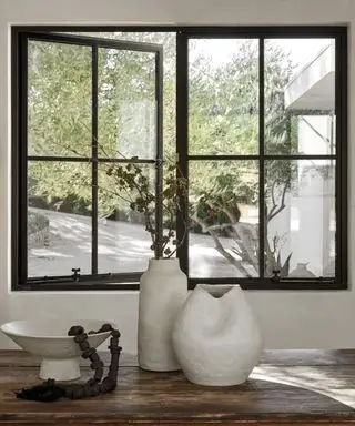 Ein schwarz gerahmtes Fenster mit einer Blumenvase