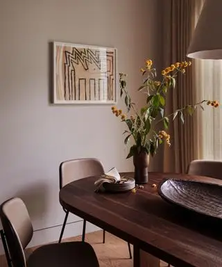 Ein Esszimmer im Japandi-Stil mit Kunst an den Wänden und einer Blumenvase auf dem Tisch