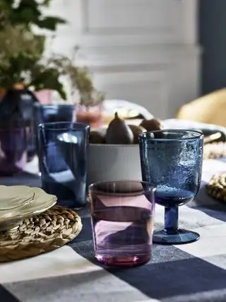 Esstischplatte mit kariertem Stoff und farbigem Glasgeschirr