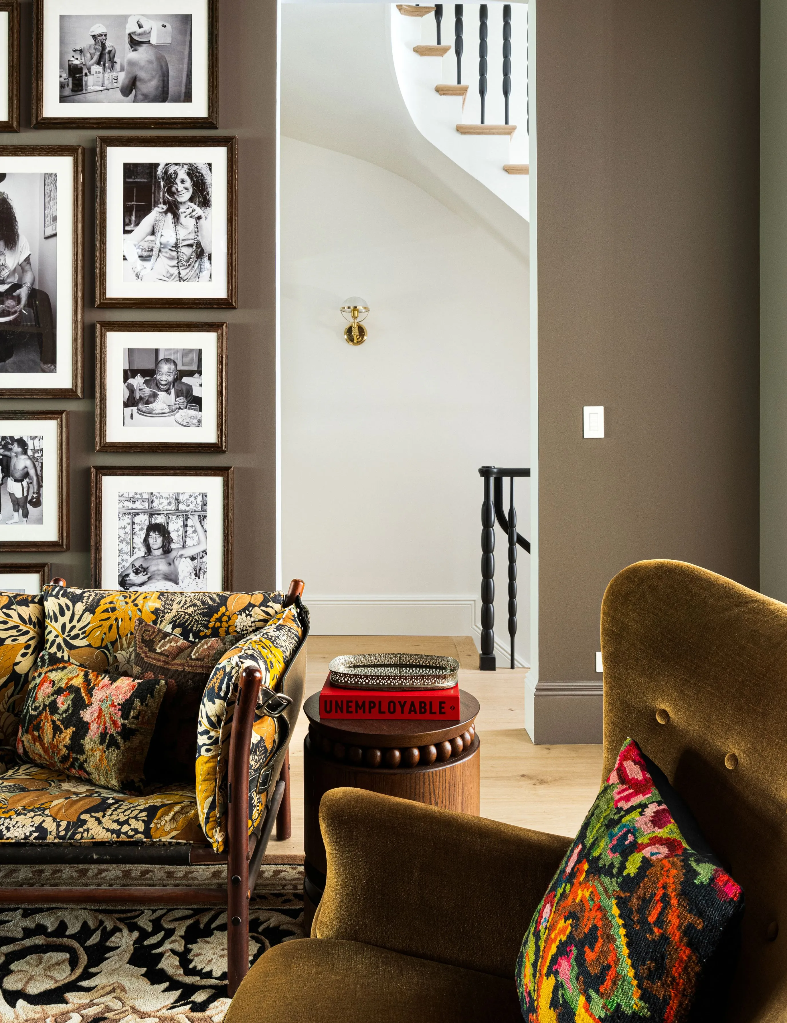 Mønsterfyldt NYC-stue med en blomstret sofa, grøn fløjls-accentstol og stakke af farverige sofabordsbøger' loading='lazy' title=