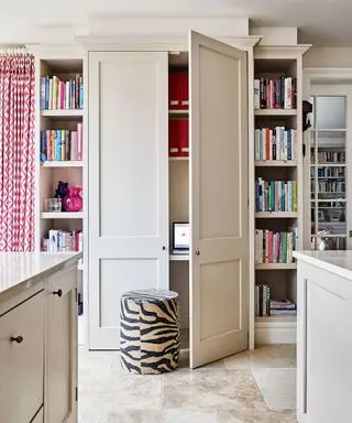 Bücherregale und maßgeschneiderte Schranktüren verbergen einen kleinen Arbeitsbereich, ein Hocker ist mit Stoff mit Zebramuster bezogen.