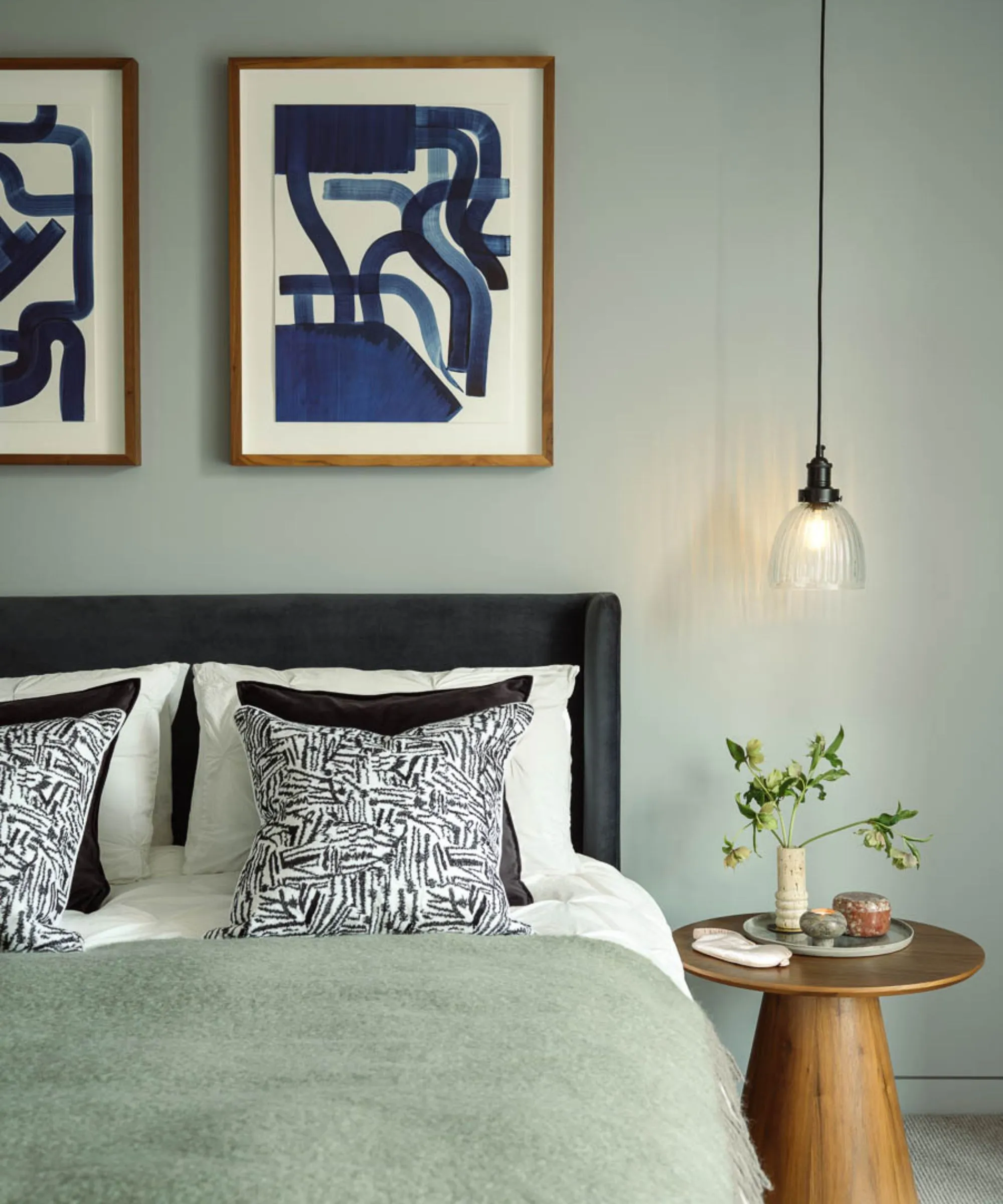 Sabio dormitorio verde con arte de pared abstracto cama doble con lanzamiento de lana de salvia y mesa redonda de madera' loading='lazy' title=