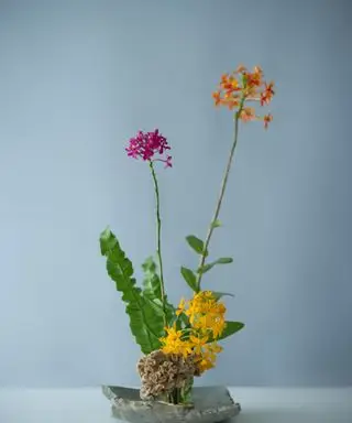 Un arreglo floral de Ikeaba con flores de color púrpura y naranja brillantes.