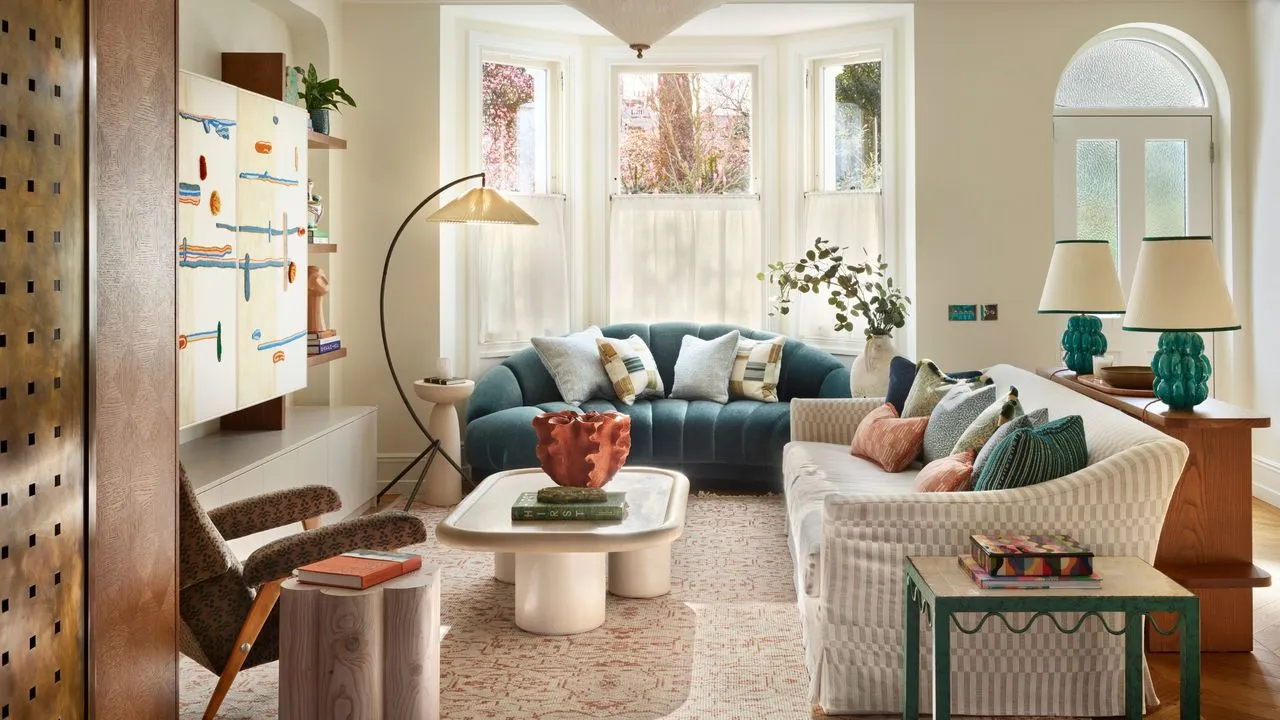 nøytral stue med stort karnappvindu en blågrønn fløyelssofa med et salongbord i stein stor gulvlampe sofa med glidelås stylet med et bord bak med to blågrønne lamper' loading='lazy' title=