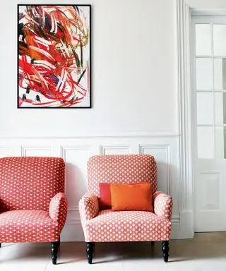 Quarto branco com arte moderna e cadeiras rosa