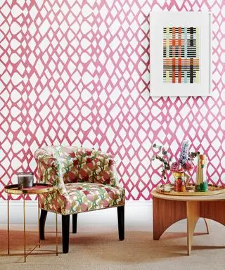 Quarto rosa com papel de parede padrão rosa e branco, mesa e cadeira de tecido