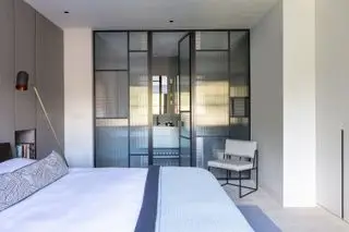 Chambre avec lit, lampadaire et vue sur une armoire avec portes vitrées