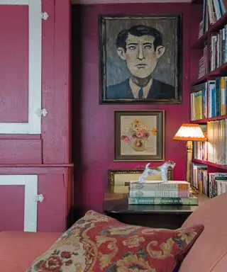 Rosa Wohnzimmer mit rosa gestrichenen Wänden und Kissen, Büchern und Gemälden an den Wänden