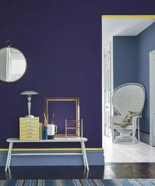 Un mur violet aubergine avec des moulures peintes en jaune