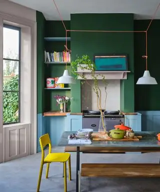 Cuisine verte et bleue avec table à manger en bois, sol gris, suspensions basses