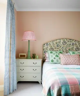 Chambre rose, lit avec literie colorée, table de chevet, lampe de table colorée, rideaux à motifs, tapis gris
