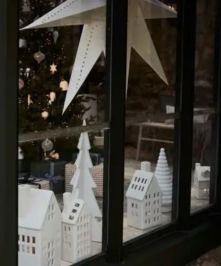 Keramik-Hausornamente und Papiersterndekoration im Fenster ausgestellt