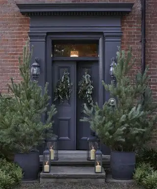 Weihnachtsbäume im Freien, Laternen und Kränze an der Haustür
