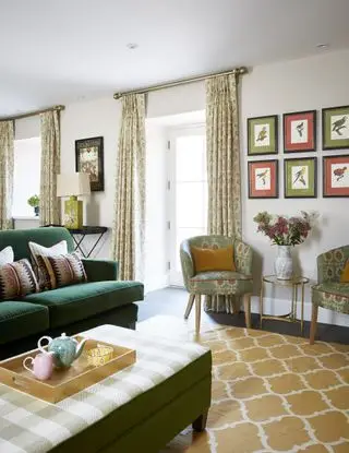 salón con cortinas francesas, alfombra amarilla, sofá verde, obras de arte en los sillones de las paredes