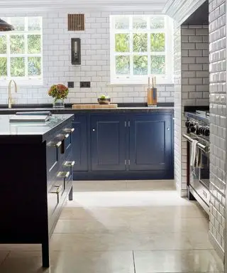 Cucina con mobili indaco e parete con piastrelle metro