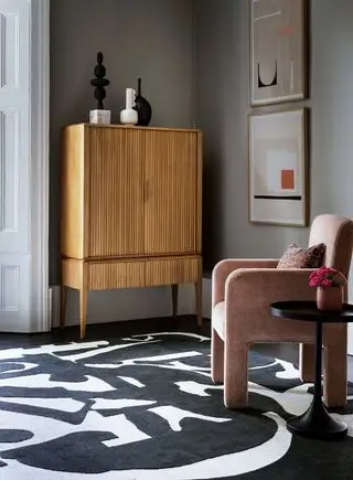 Sala de estar cinza com tapete preto e branco e cadeira rosa blush