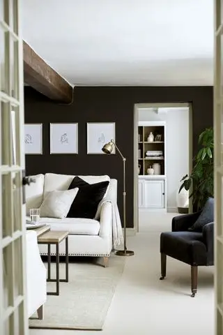 Paredes pretas da sala de estar com sofá branco e obras de arte
