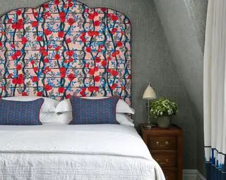 Ein auffälliges blau-rot gemustertes Kopfteil von Kit Kemp in einem kleinen Schlafzimmer.