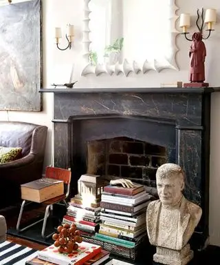 Chimenea decorada con libros y adornos antiguos.