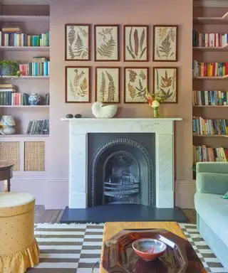 Dormitorio rosa con pared de galería, chimenea y estanterías tipo alcoba.