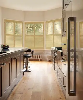 moderne Küche mit dunklen Schränken, hellen Eichenböden und zartgelben Fensterläden