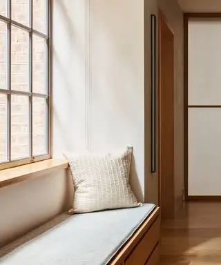 En sittehjørne ved et stort vindu i et rom i japansk stil