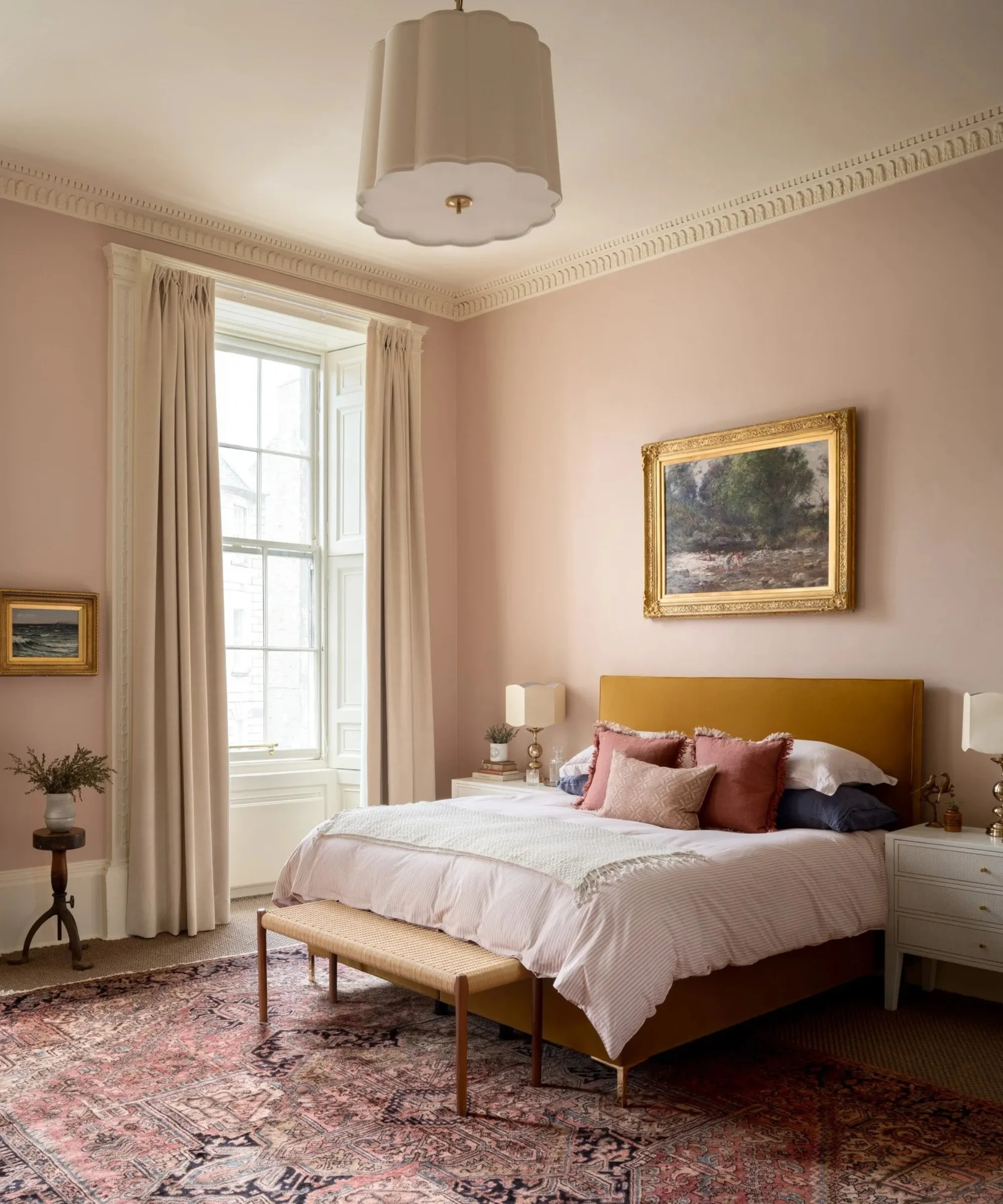 天井が高い寝室 ピンク色に塗られた壁 大きな窓 からし色のベッドフレーム 枕がいくつか置かれたベッドと床にはペルシャ絨毯が敷かれている' loading='lazy' title=
