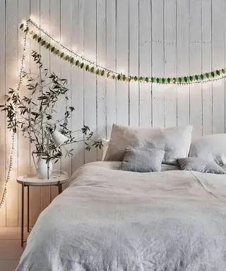Guirlandes lumineuses, table de chevet blanche, draps gris