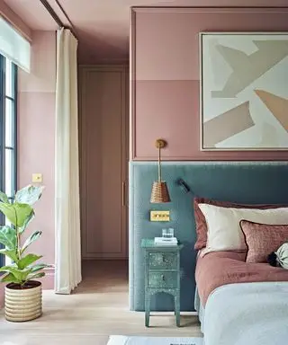 Dormitorio con paredes rosas y cama con cabecera verde de gran tamaño.