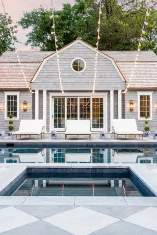 Piscina con tumbonas y casa.