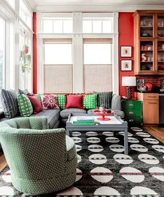 sala familiar con paredes rojas, sofá gris, sillón verde y alfombra blanca y negra