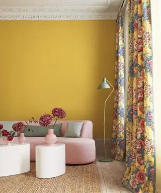 En stuegardinidé med gule vegger, rosa sofa og gule blomstergardiner