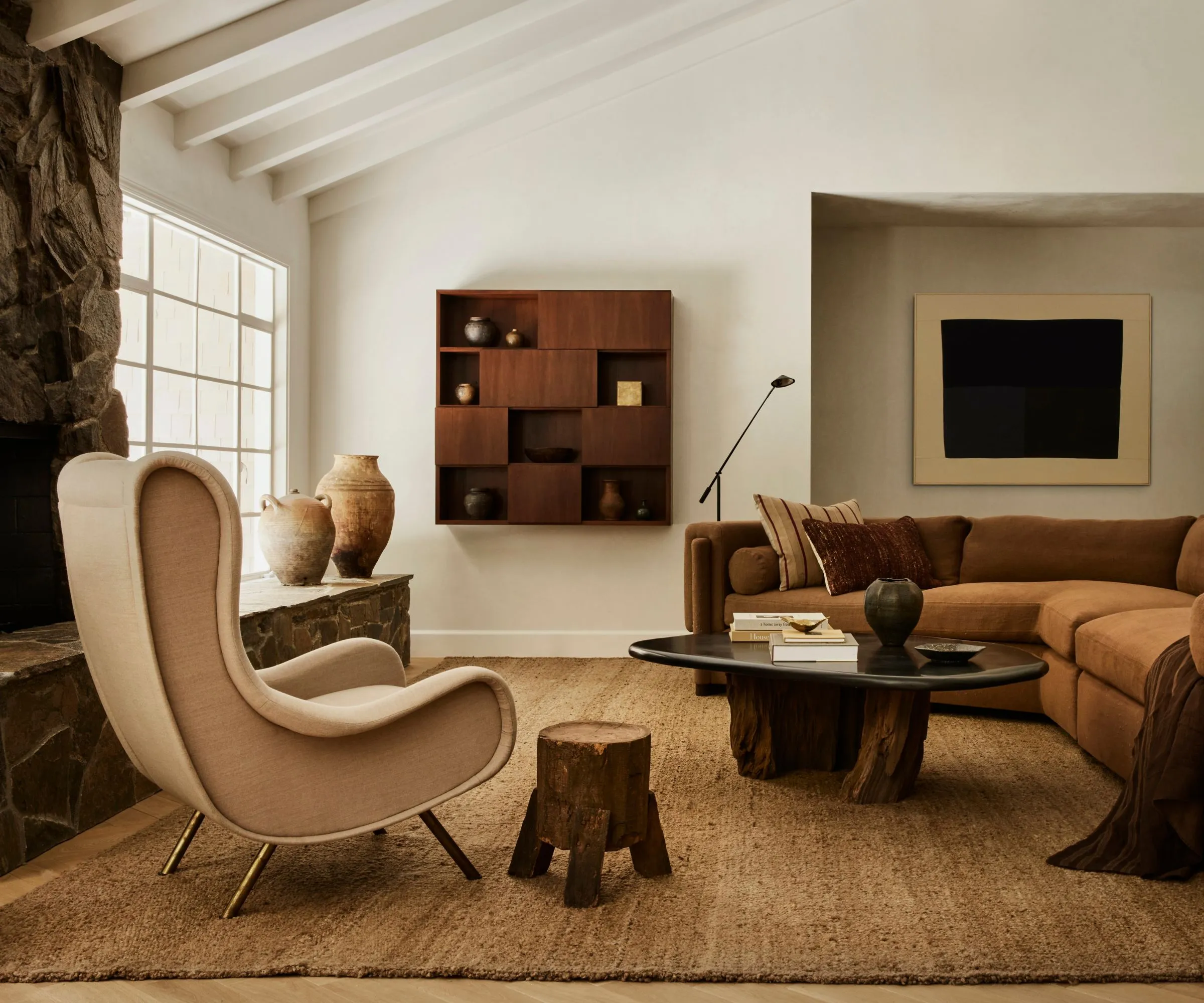 neutrálny útulný vintage sa stretáva s modernou obývacou izbou s trámovým stropom kamenný krb v plnej výške rohová pohovka textúrovaný tkaný koberec' loading='lazy' title=