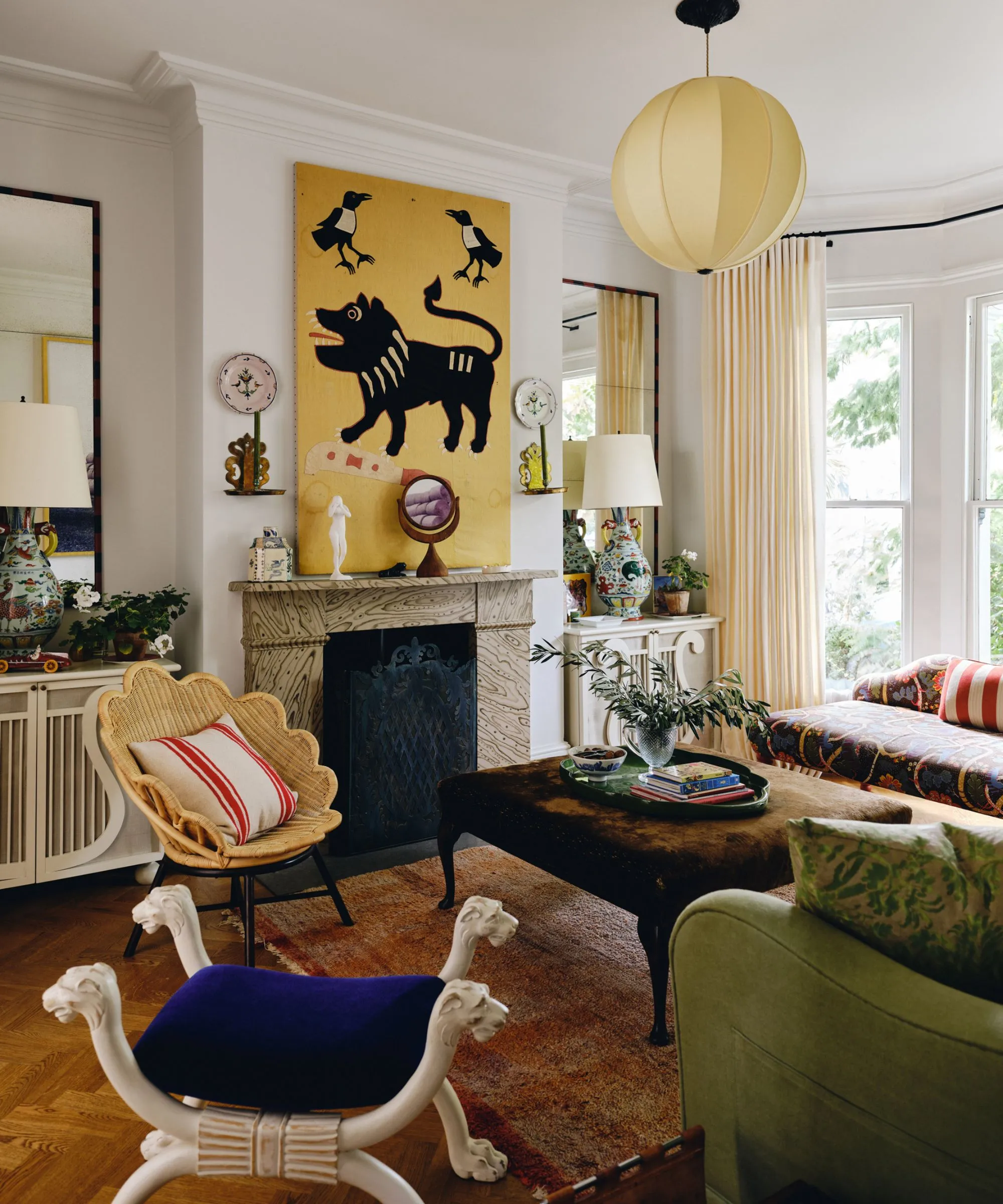 obrázok eklektickej obývačky s bielymi stenami a veľkým žltým obrazom nad mramorovým krbom s vrúbkovaným ratanovým kreslom a eklektickým nábytkom' loading='lazy' title=