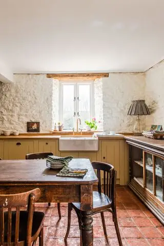 Cocina vintage con paredes de ladrillo pintado de blanco, gabinetes y encimeras de madera y un mostrador recuperado que sirve como espacio de trabajo adicional Cocina edit58 de British Standard de Plain English
