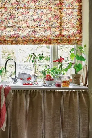 fregadero de cocina vintage con gabinetes con cortinas y persiana romana floral sobre la ventana