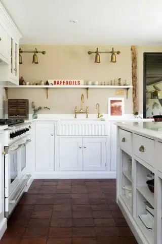 Cocina vintage blanca con suelo de baldosas de terracota roja y paredes color crema