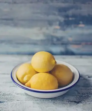 Limões em uma tigela sobre uma mesa de madeira