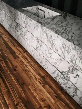 ダーク色の再生木のキッチン床と並んで大理石のカウンター。