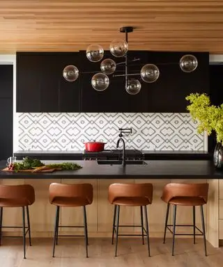 você pode colocar uma ilha em uma cozinha de galé, cozinha preta e de madeira com bancos de bar, backsplash de estilo gráfico, bancadas pretas e armários de parede