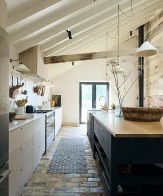 Cocina rústica moderna deVOL con gabinetes de madera de Sebastian Cox, vigas en el techo y piso de ladrillo