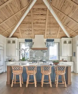 Amplia cocina en una propiedad de nueva construcción con una gran isla de cocina azul y un techo alto revestido de madera de ciprés