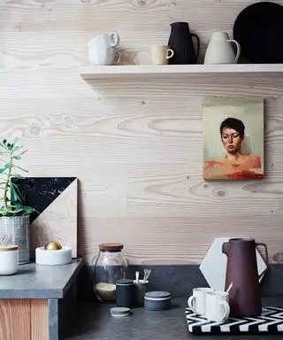 Skromná moderná kuchyňa s drevenou stenou a olejovým portrétom.
